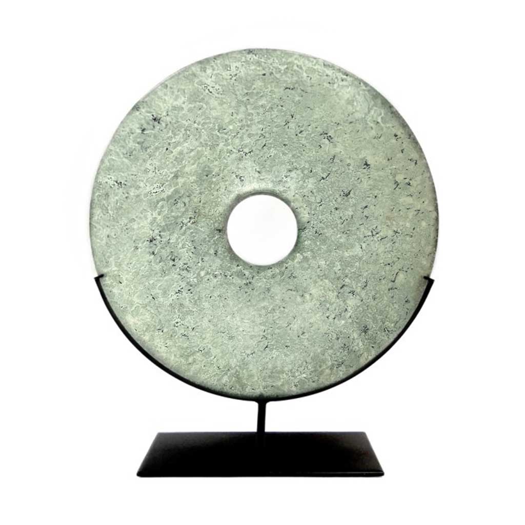 Green flecked marble bi disc displayed on a bronze stand.