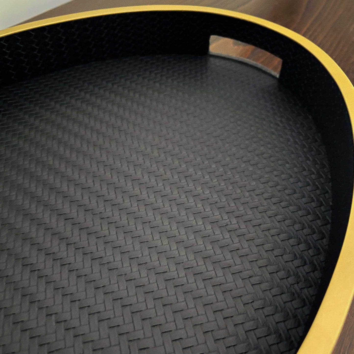 Close up of oval black textured leather with gilt trim and handles