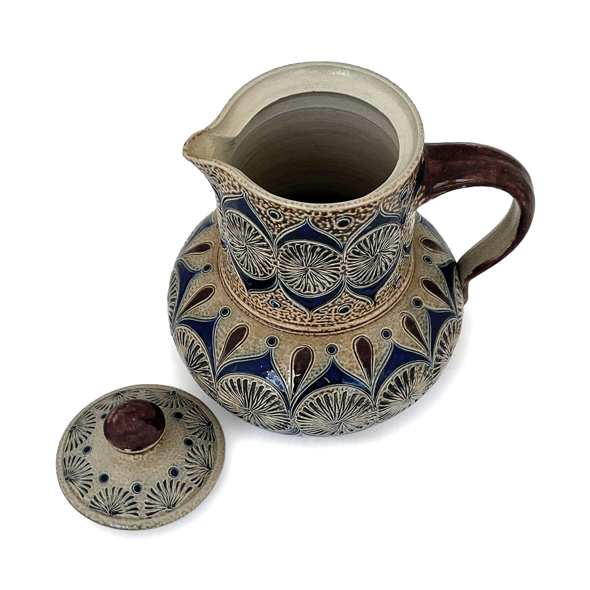 Small coffee pot with decoration and engraved details in blue and brown seen from above with lid off.