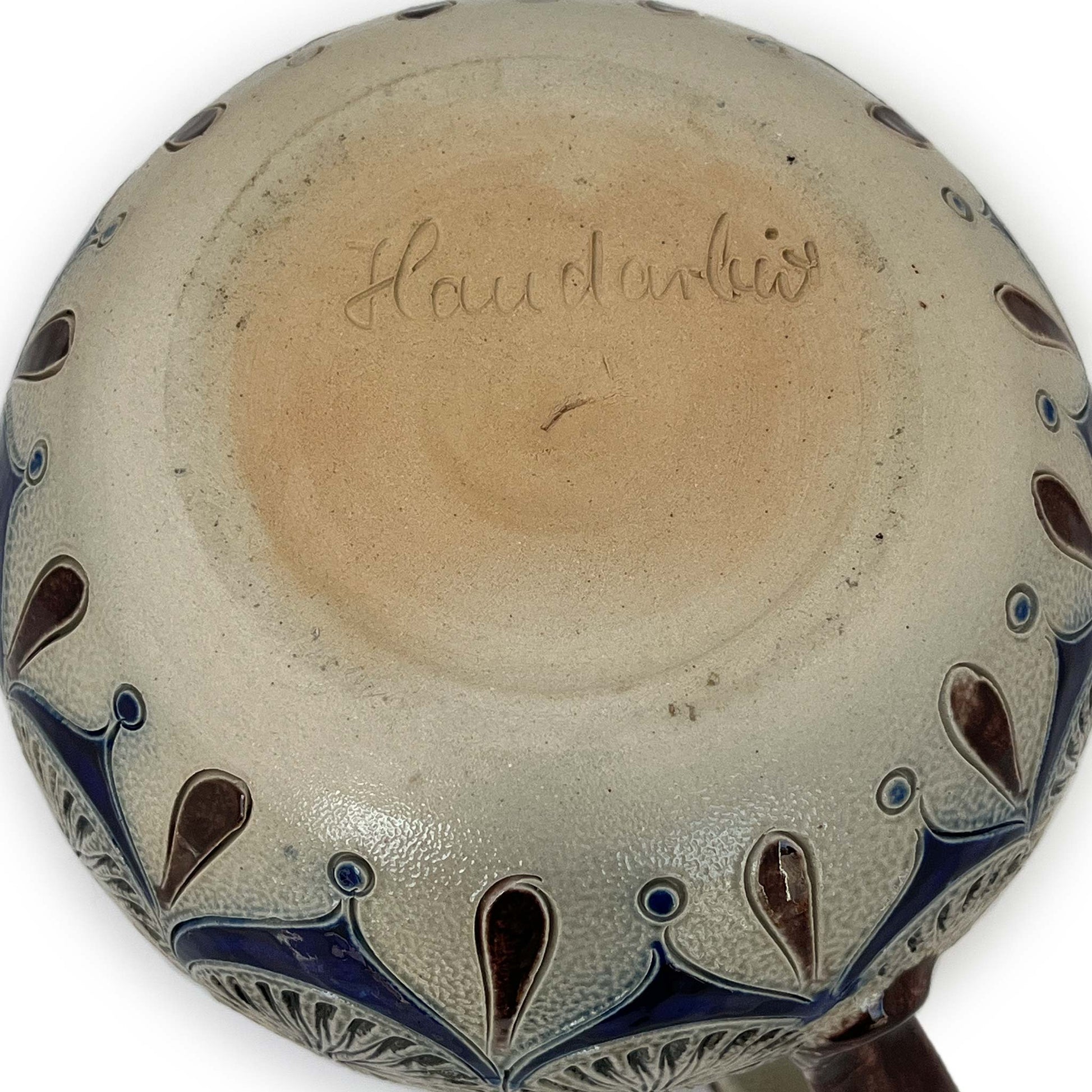 Base of small coffee pot with decoration and engraved details in blue and brown with Handarbeit enscribed.