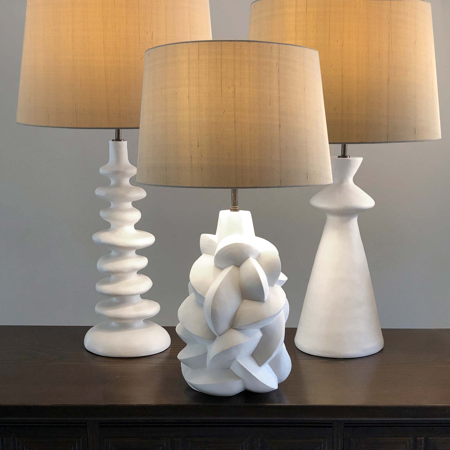 Lifestyle image of collection of three white jesmonite plaster lamps