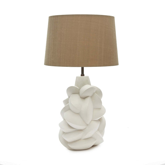 Art deco style table lamp with a jesmonite plaster body comprising of fragments and facets, resembling cubist sculptures. It is shown with a beige tapered linen lampshade