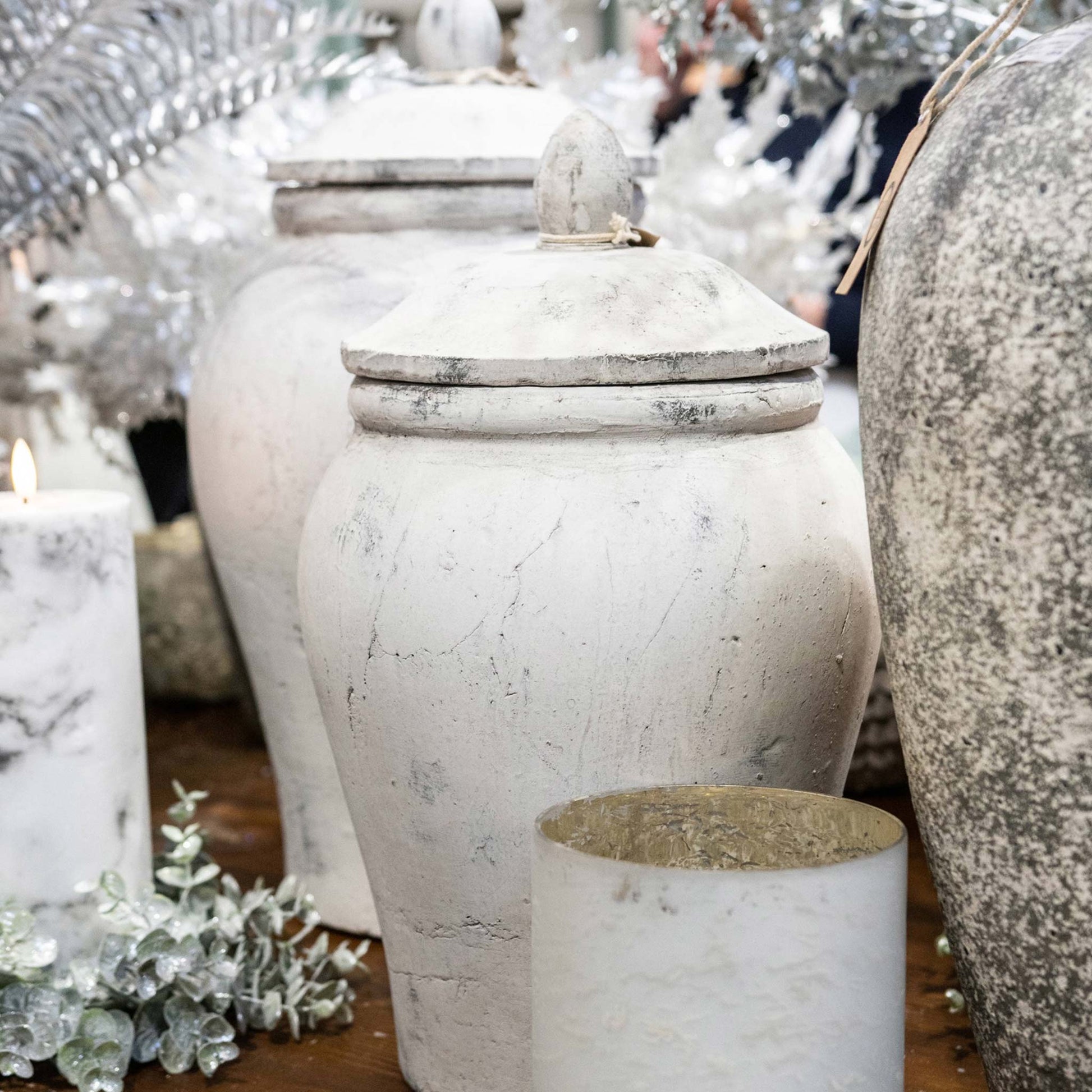 Lifestyle image of two rustic white ginger jars in decorative winter scene