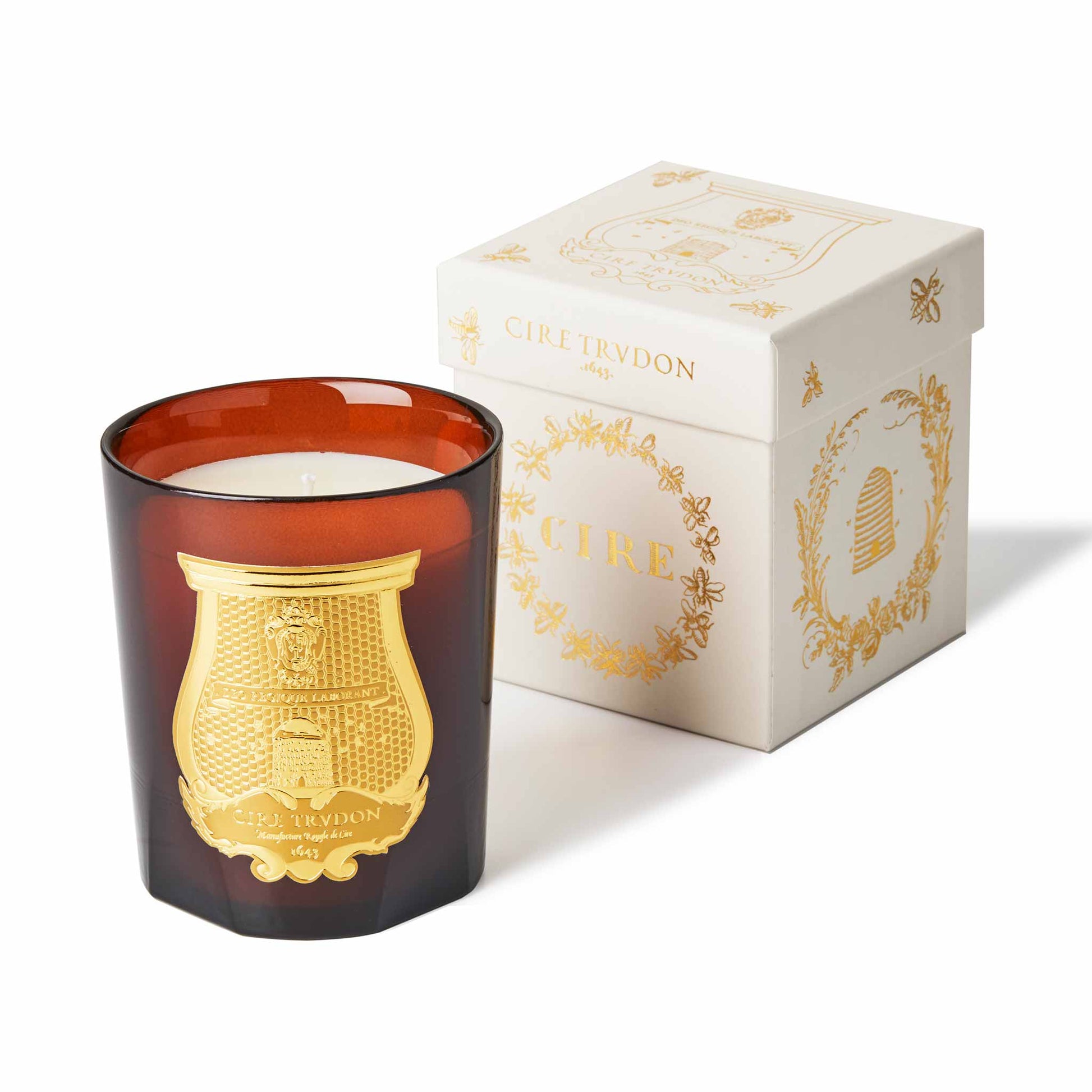 cire trudon candle in a red glass jar with a luxury gold label. this candle comes in a white box with gold detailing