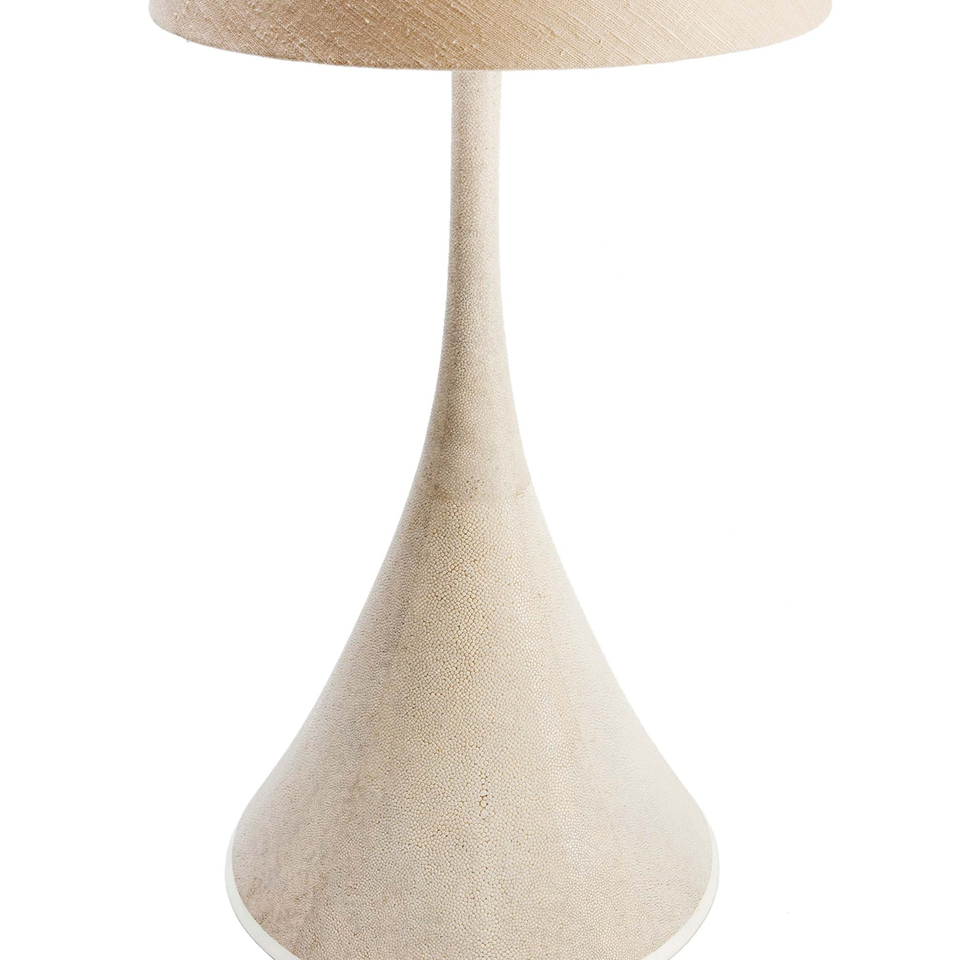 Close up of Cone shaped table lamp covered in a natural shagreen finish, completed with a thin layer of protective lacquer and a base of creamy white bone. the lamp is shown with a beige tapered linen lampshade