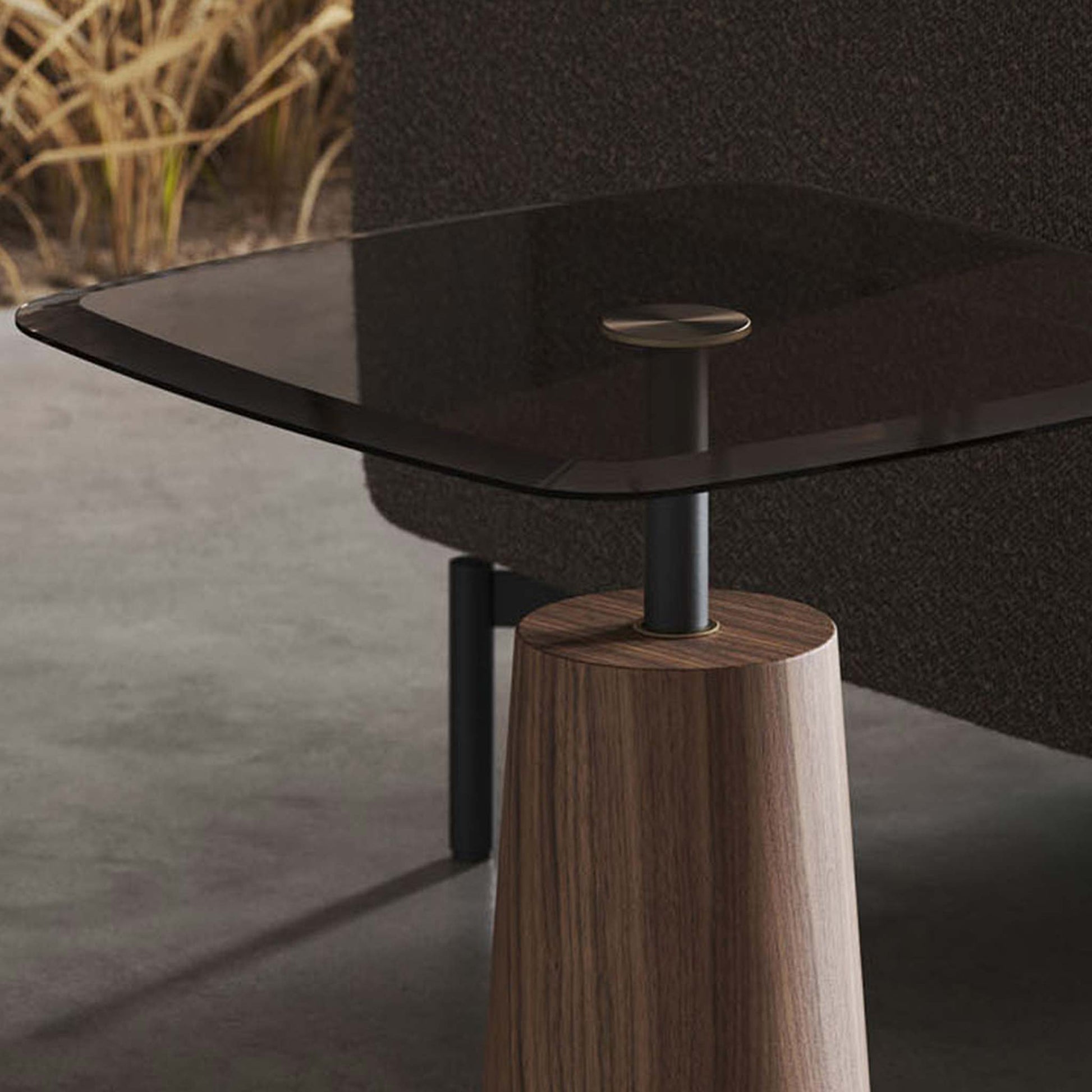 Lifestyle image showing close up of modern smoked glass accent table on pedestal in modern living room