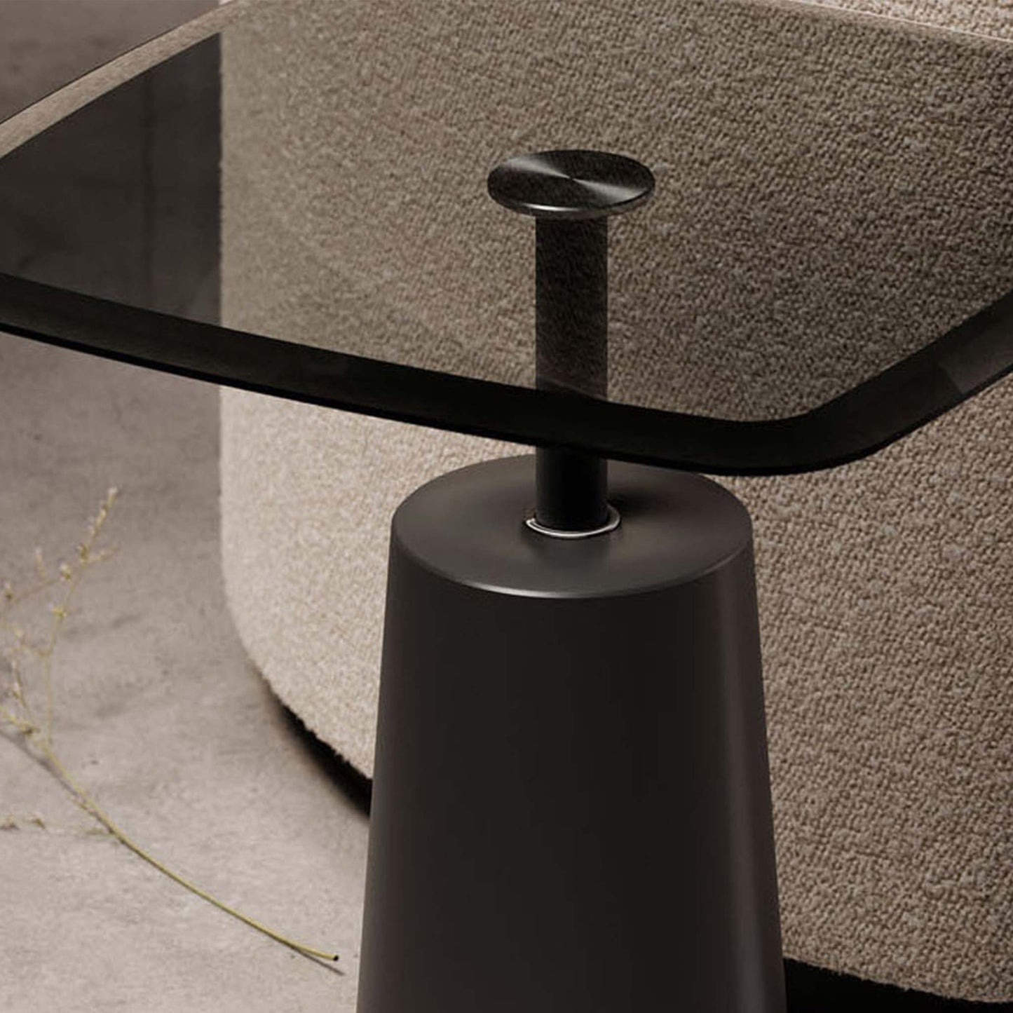 Lifestyle image showing close up of modern smoked glass accent table on pedestal in modern living room