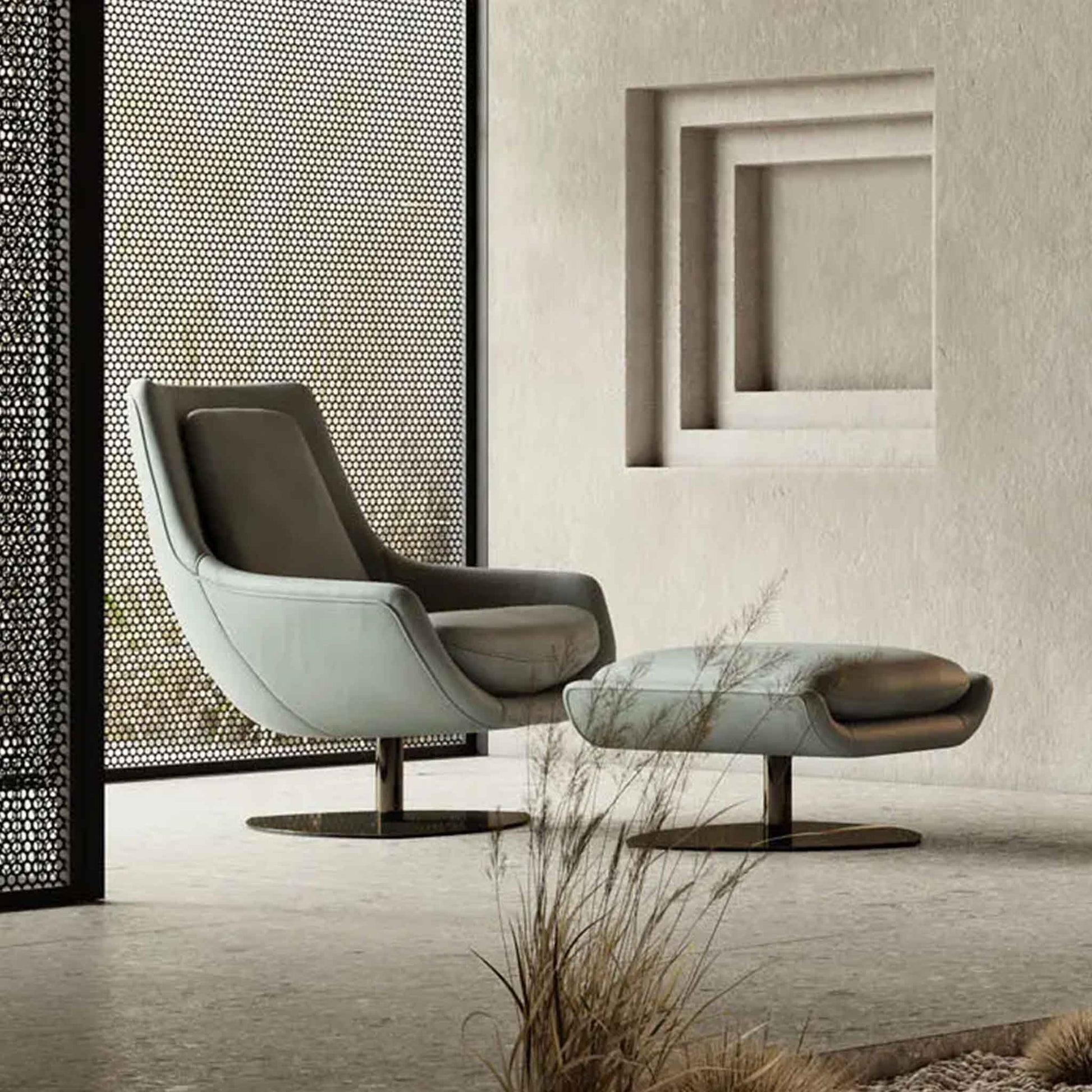 Lifestyle image in modern setting with stone floor of modern egg shaped swivel chair with light grey leather upholstery on pedestal steel base. Shown with matching footstool.