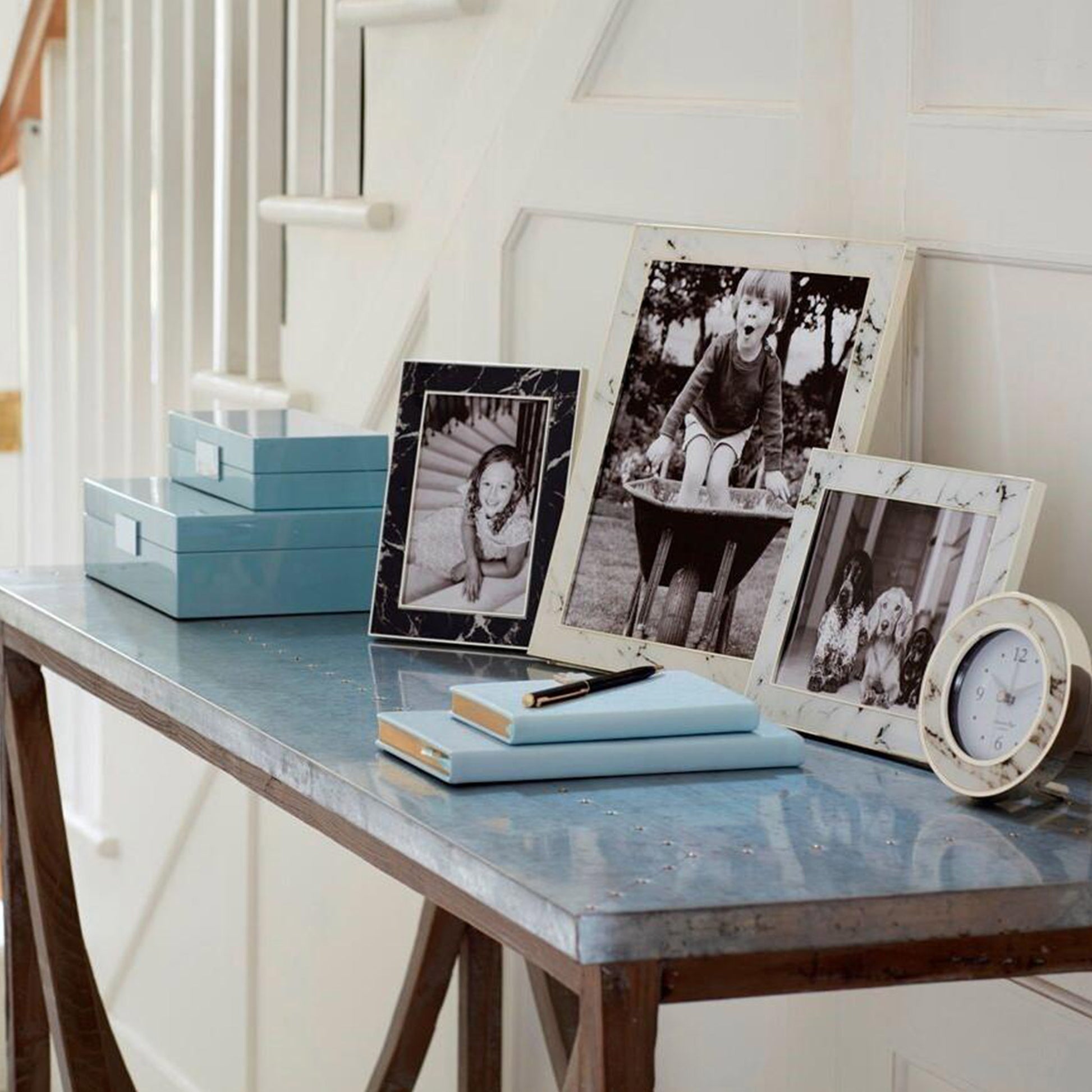 Lifestyle of black and white marble and silver photo frames on a hallway table.