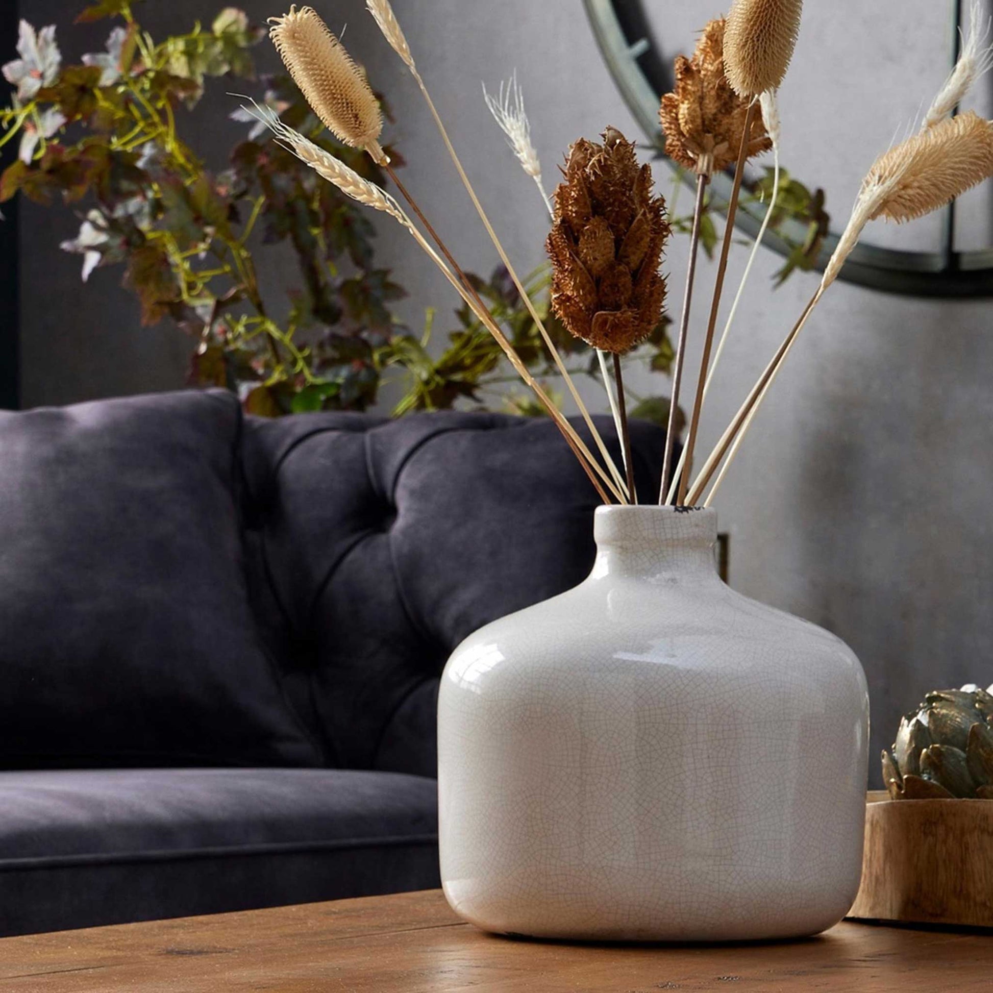 Lifestyle image of white crackle glazed vase with a wide full form form and a small tapered neck.