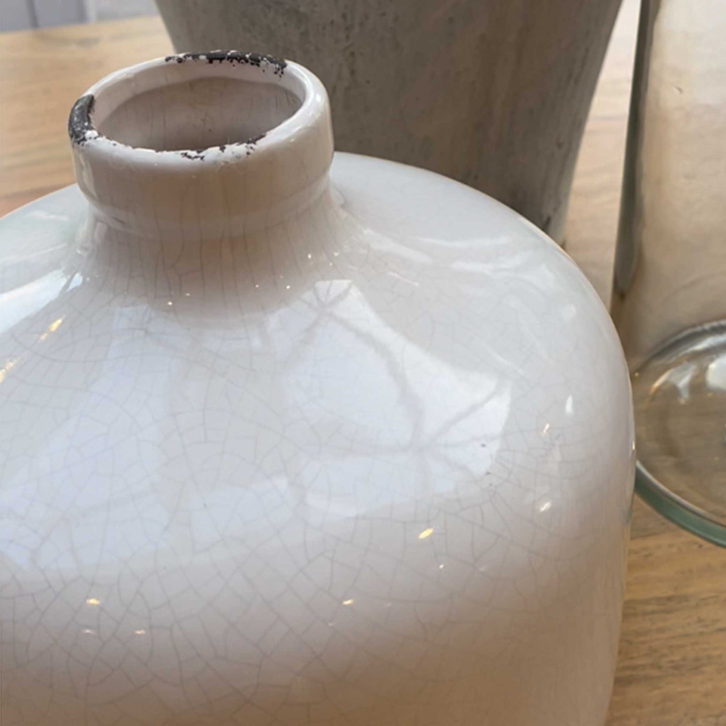 Close up image of white crackle glazed vase with a wide full form form and a small tapered neck. 