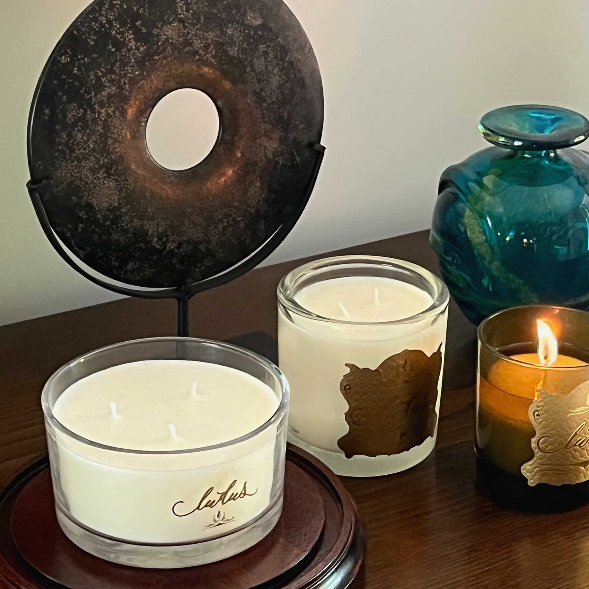 Lifestyle image of a three luxury Ludus candles. Displayed in a hallway with a marble bi-disc.