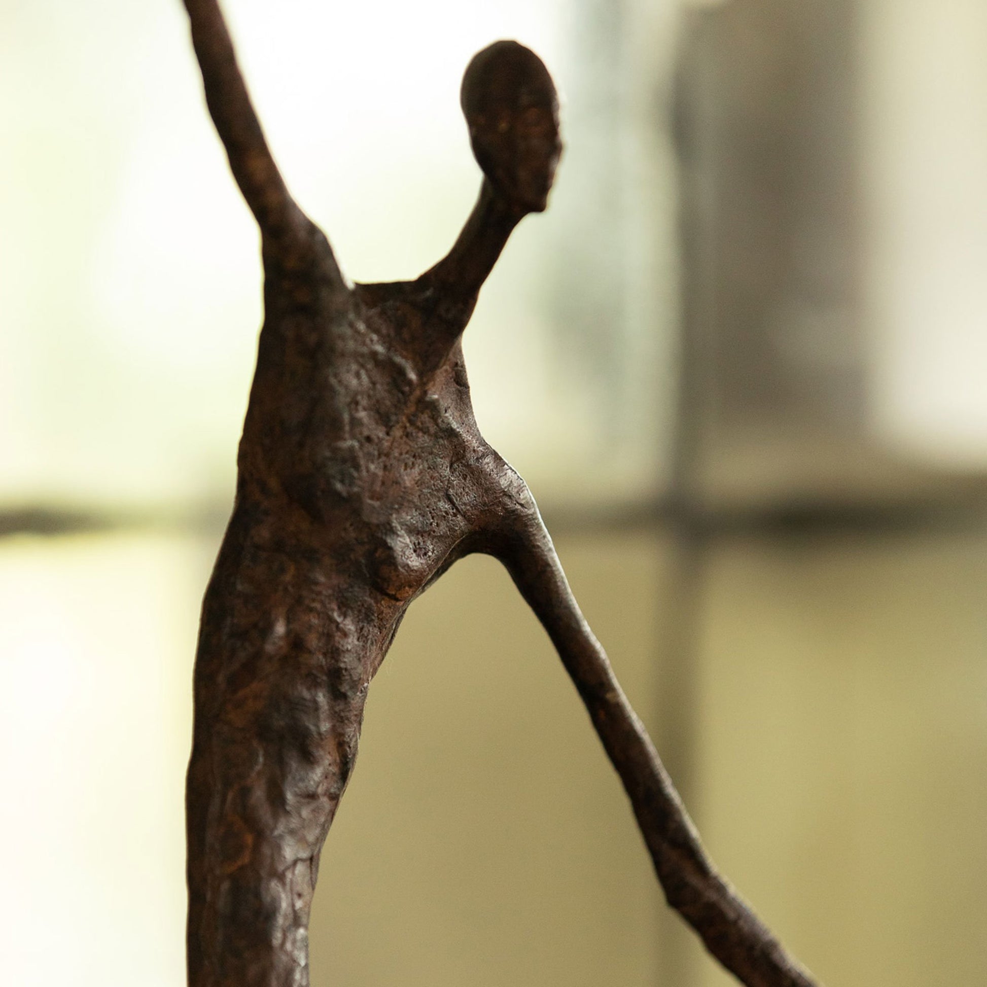 Close up of luxury bronze Giacometti style figure with hoop and stick. Displayed on a square bronze base.