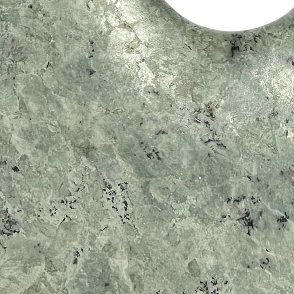 Close up of green flecked marble bi disc displayed on a bronze stand. 