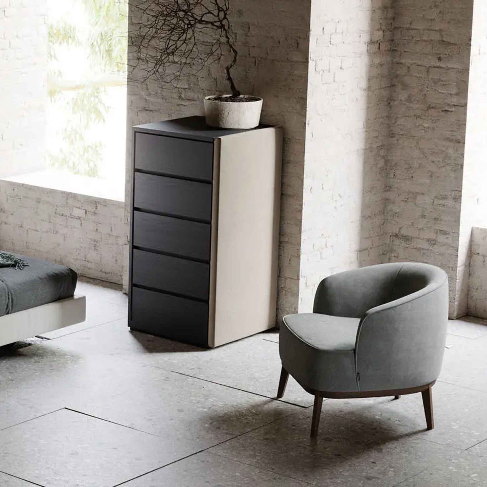 Lifestyle image of modern and minimal tub style armchair in grey velvet upholstery. Shown in minimal apartment with white brick walls and stone floor. View from above.