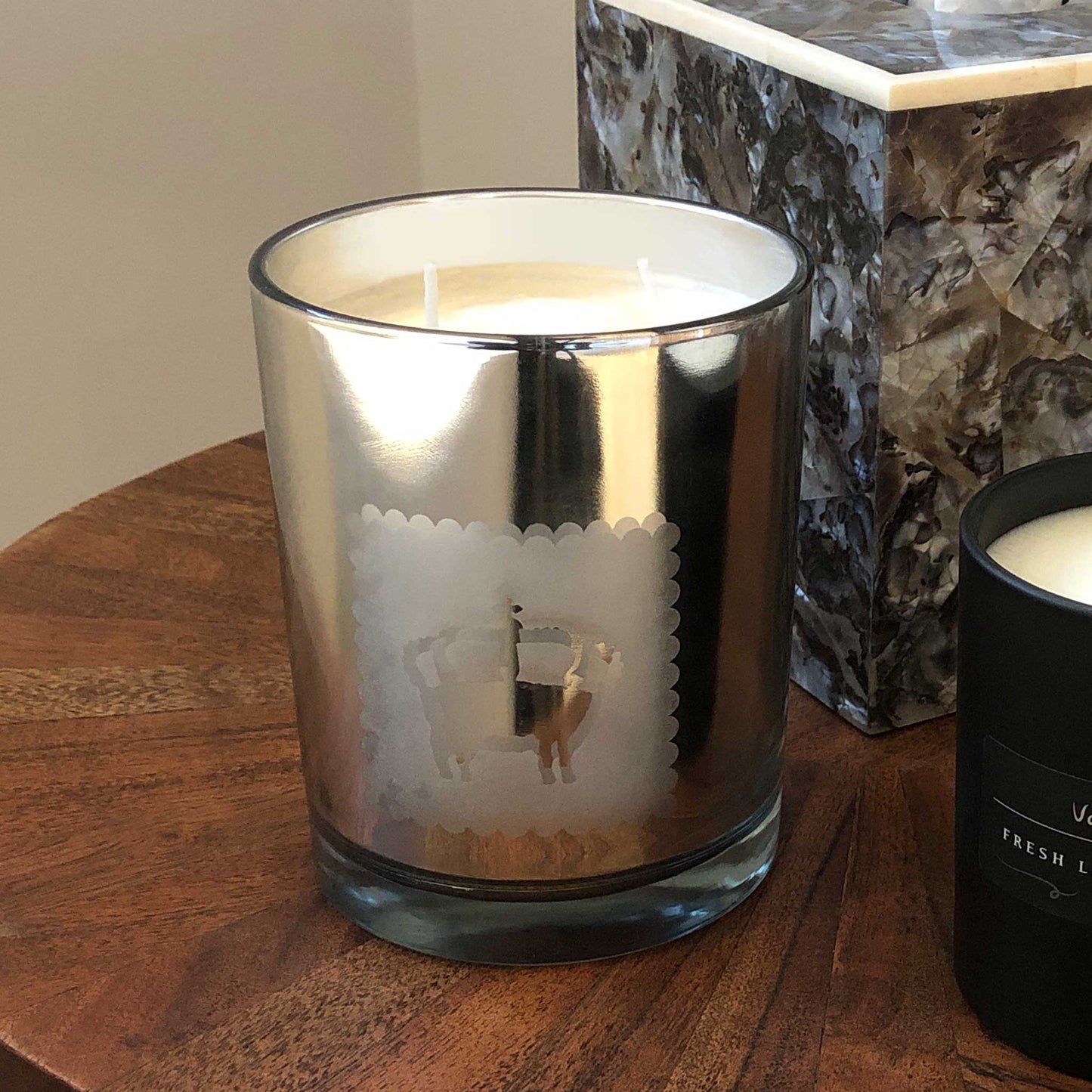 Close up of lavender candle in modern silver metallic jar. Displayed on a side table.