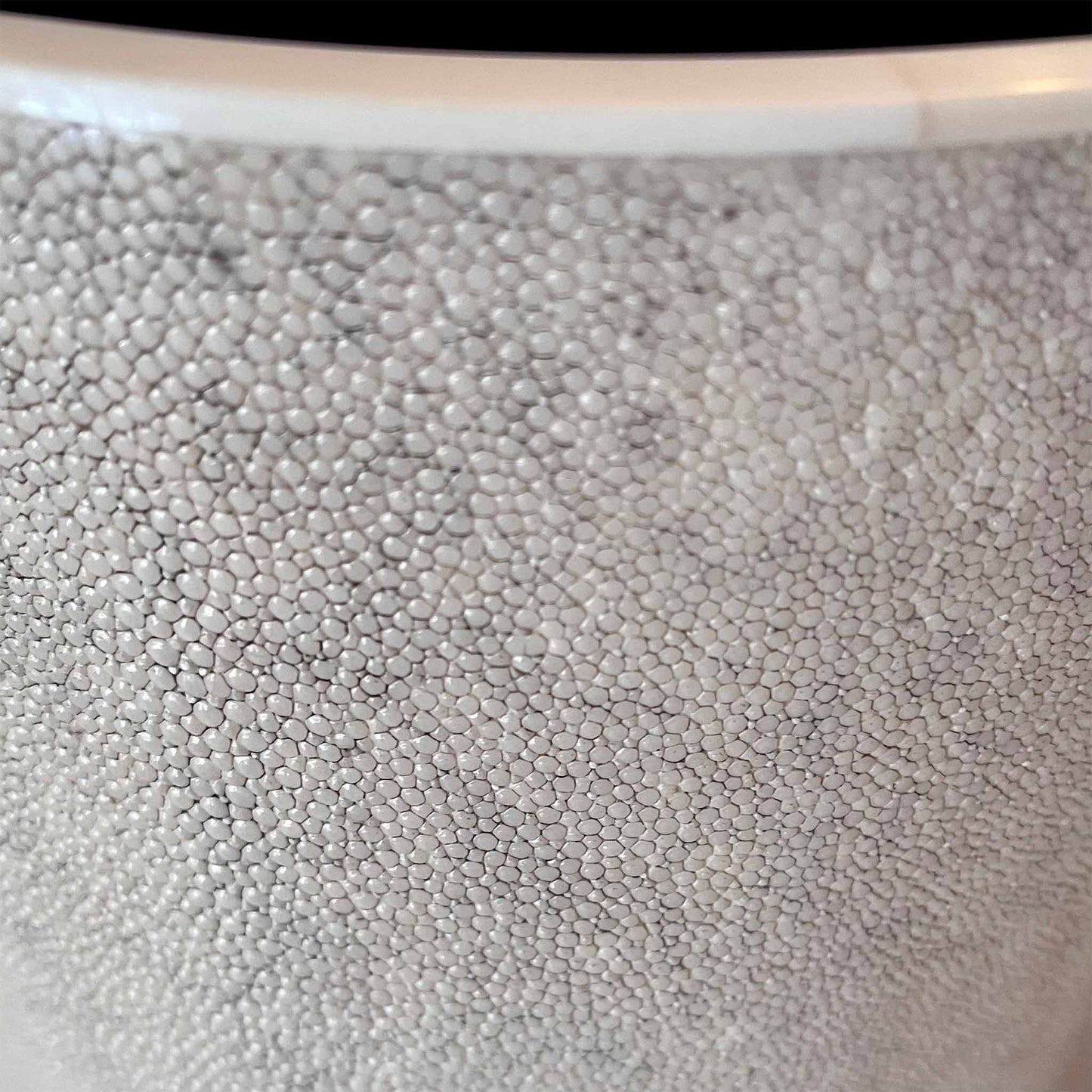 Close up of cylinder waste bin in a natural shagreen and rimmed with a creamy white polished bone edge