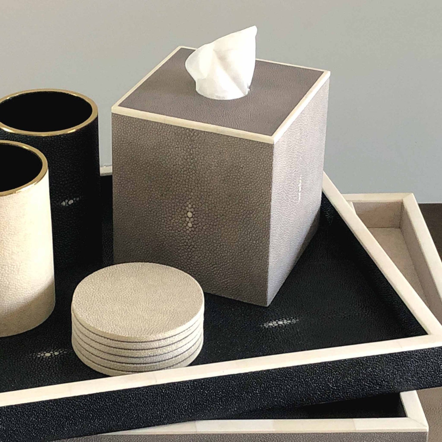 Lifestyle image of square grey shagreen luxury tissue box with white bone trim. Displayed with other shagreen trays, coasters and pen pots.