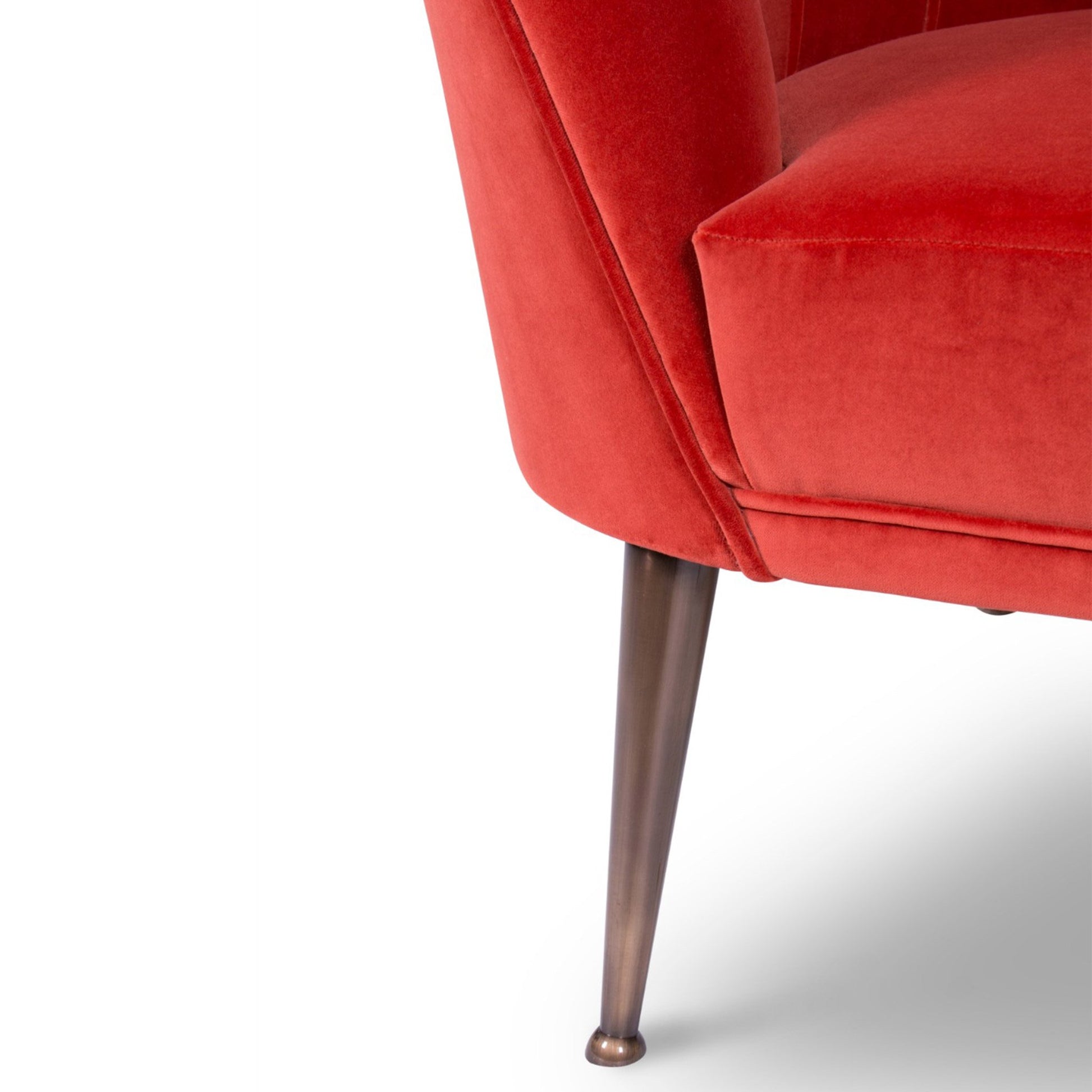 close up image showing the matte aged brass legs of the red mid-century modern armchair